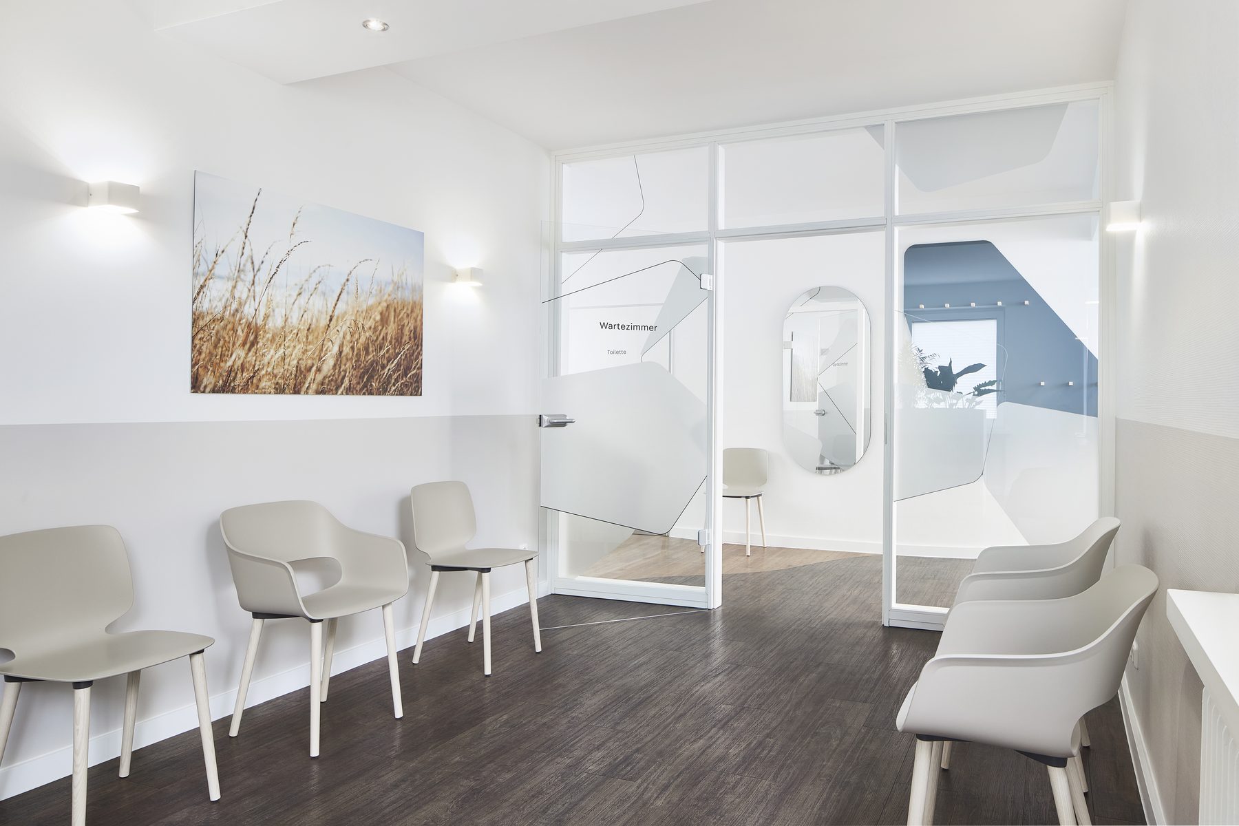 Wartebereich mit hellen Stühlen entlang der Wand und Blick durch die Glaswand ins Wartezimmer